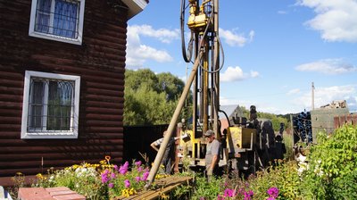 Буровая машина на участке с рабочими летом